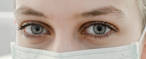Regard d'une femme aux yeux bleus derrière un masque chirurgical